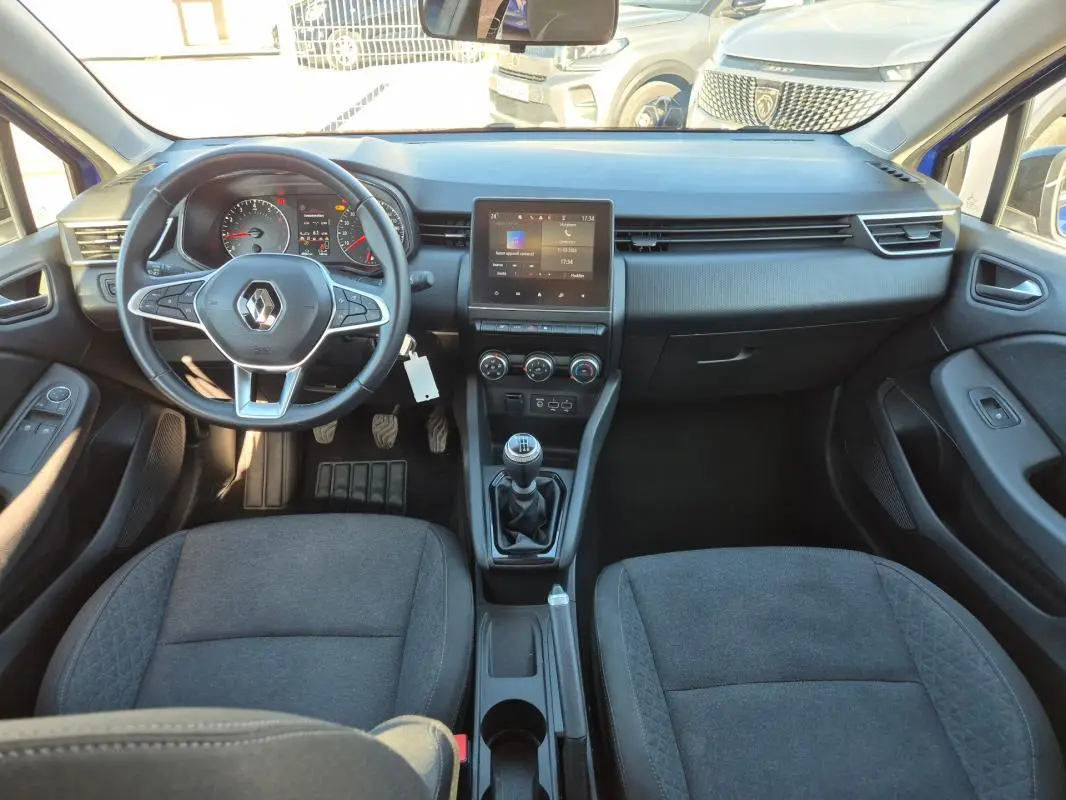 Vue intérieure avant de la Renault Clio V TCe 90 Equilibre 2023, tableau de bord noir avec écran tactile et boîte manuelle.