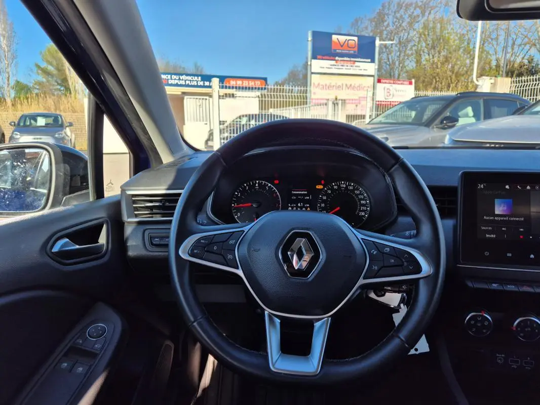 Vue intérieure centrée sur le volant de la Renault Clio bleu foncé 2023 avec tableau de bord et écran tactile visibles.