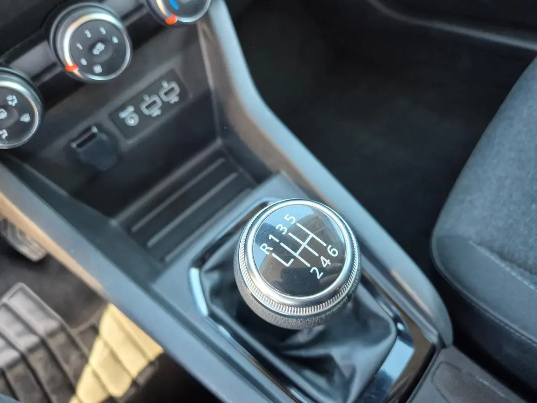 Gros plan sur le levier de vitesses manuel de la Renault Clio V TCe 90, entouré de la console noire et siège gris.