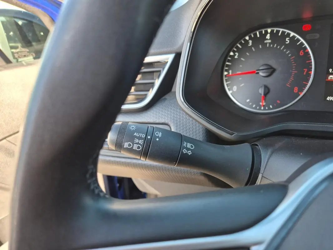 Gros plan sur le commodo des phares et clignotants côté gauche du volant d'une Renault Clio bleu foncé 2023.