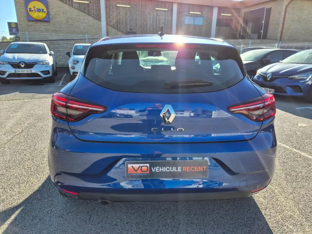 Vue arrière d'une Renault Clio bleu foncé 2023, avec feux arrière allumés et plaque "Véhicule récent" visible.