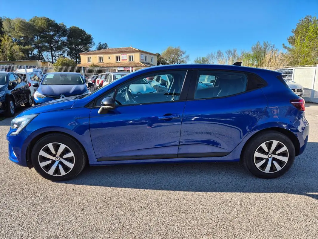 Profil latéral droit d'une Renault Clio bleu foncé 2023 garée en extérieur, avec jantes alliage distinctives.
