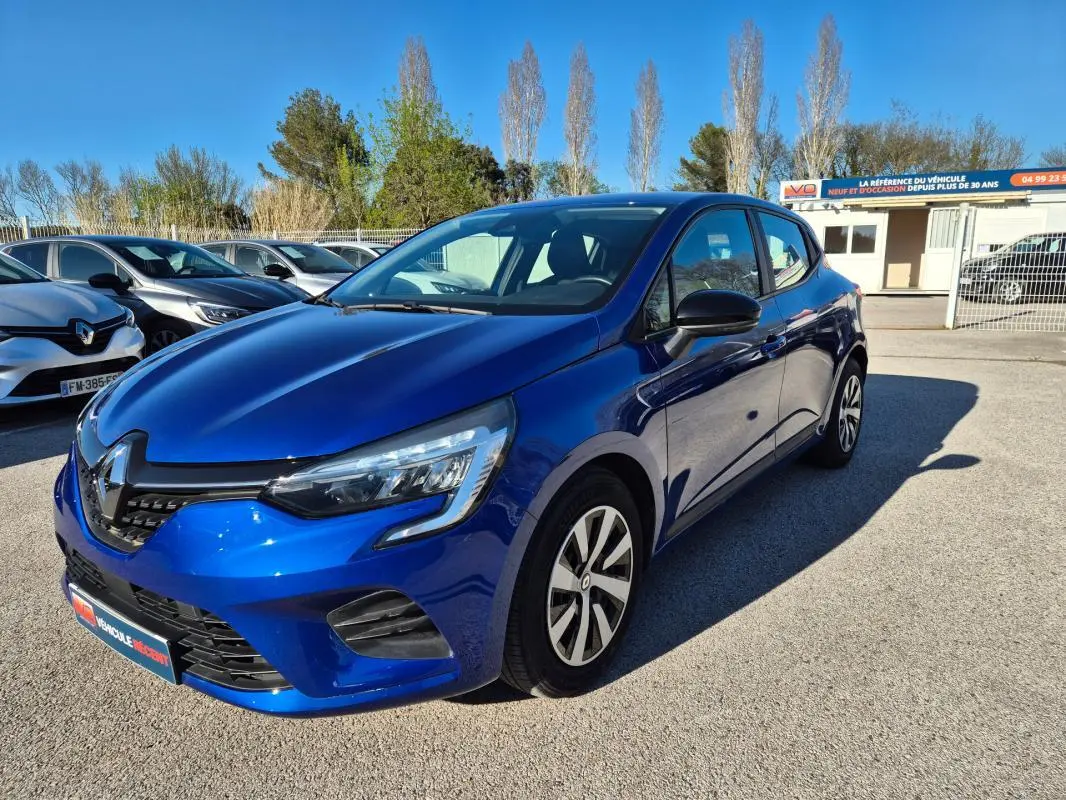 Renault Clio V TCe 90 bleu foncé vue 3/4 avant droit sur parking ensoleillé avec calandre noire distinctive.