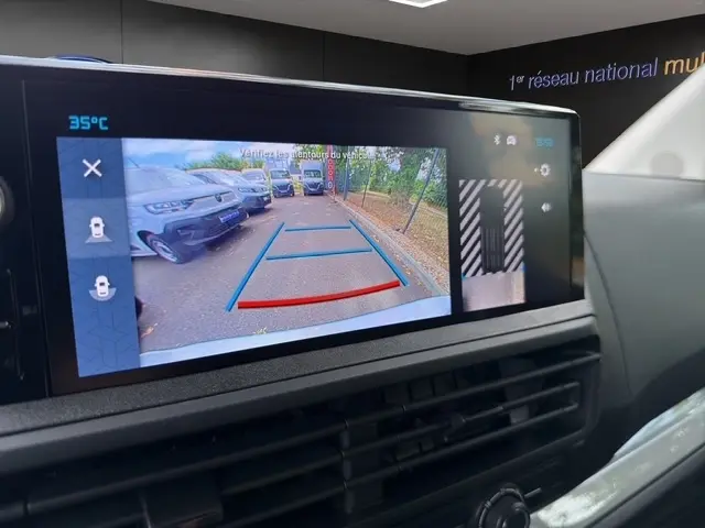 Écran de caméra de recul montrant l’arrière d’un Citroën Jumpy blanc en stationnement, avec lignes de guidage colorées.