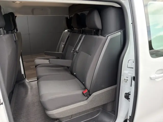 Vue intérieure côté gauche sur la banquette arrière grise du Citroën Jumpy blanc avec accoudoirs et ceintures visibles.