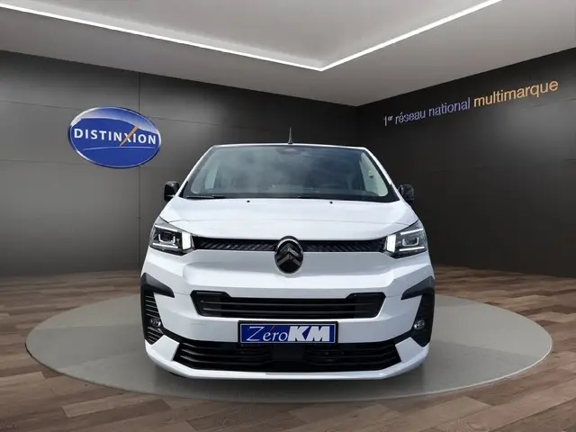 Vue avant d'un Citroën Jumpy blanc 2026 dans un showroom, avec calandre noire et phares LED distinctifs.