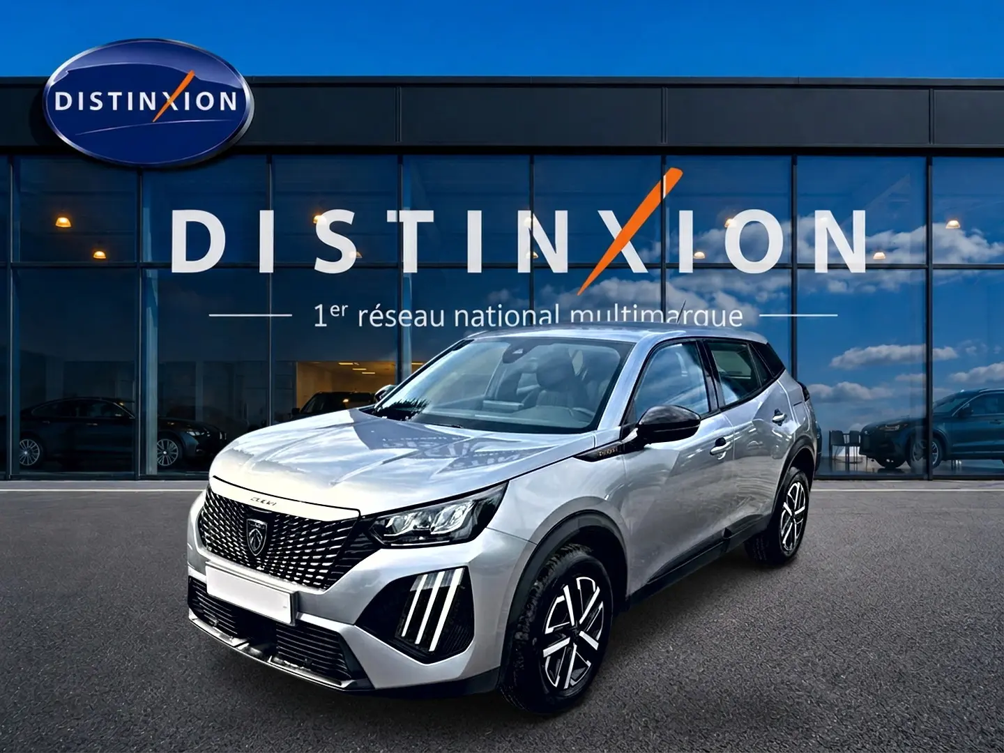 Peugeot 2008 gris en 3/4 avant droit, avec calandre noire et feux LED distinctifs, devant showroom Distinxion.
