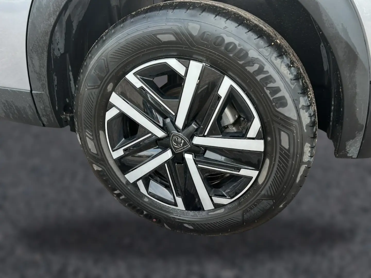 Gros plan sur la roue avant gauche du Peugeot 2008 gris, mettant en valeur la jante noire et argentée au design moderne.