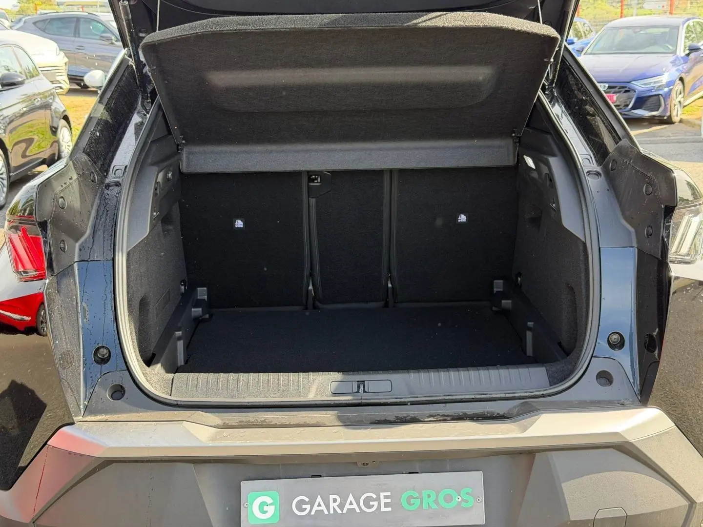 Coffre ouvert vu de l'arrière d'un Peugeot 3008 noir Perla Nera, montrant l'espace de chargement vide et la plage arrière relevée.