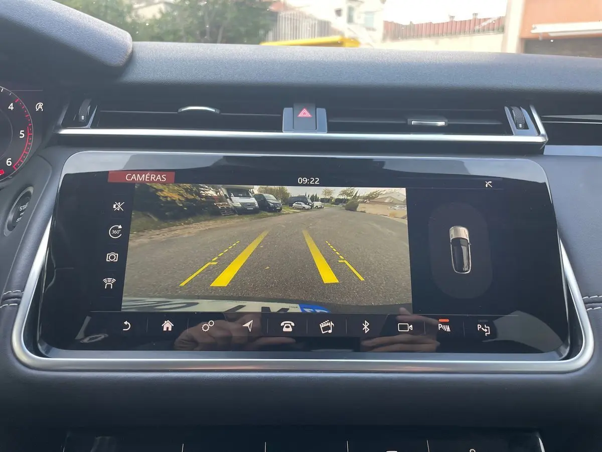 Écran central du Range Rover Velar 2019 montrant la caméra de recul avec lignes de guidage jaunes sur route grise.