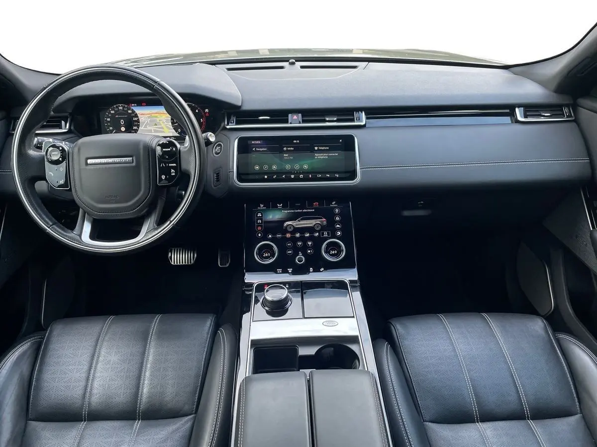 Vue intérieure du tableau de bord et console centrale du Range Rover Velar gris, avec écran tactile et volant multifonction.