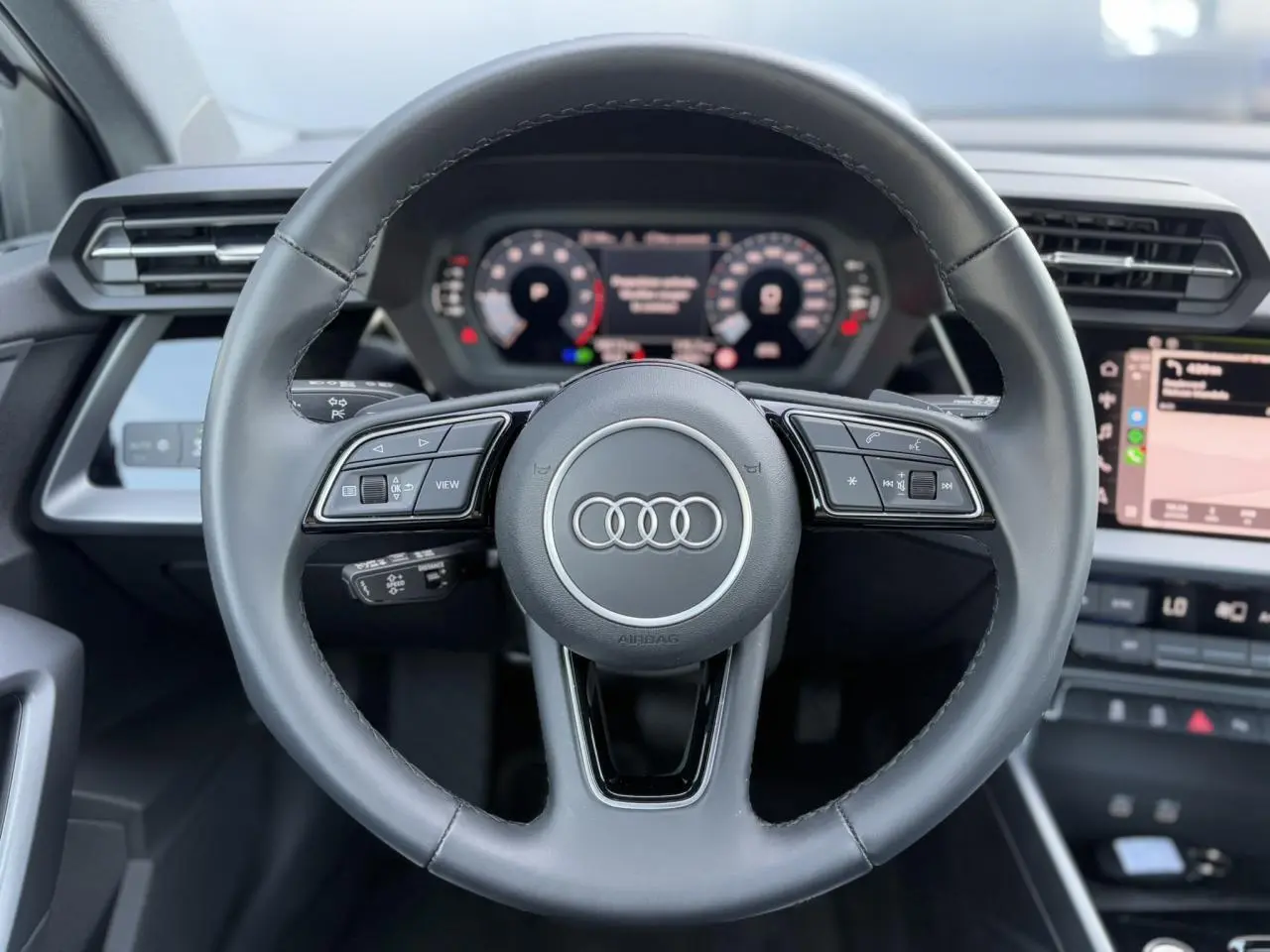 Volant cuir multifonctions de l'Audi A3 Sportback 2024 avec tableau de bord numérique et écran tactile latéral.