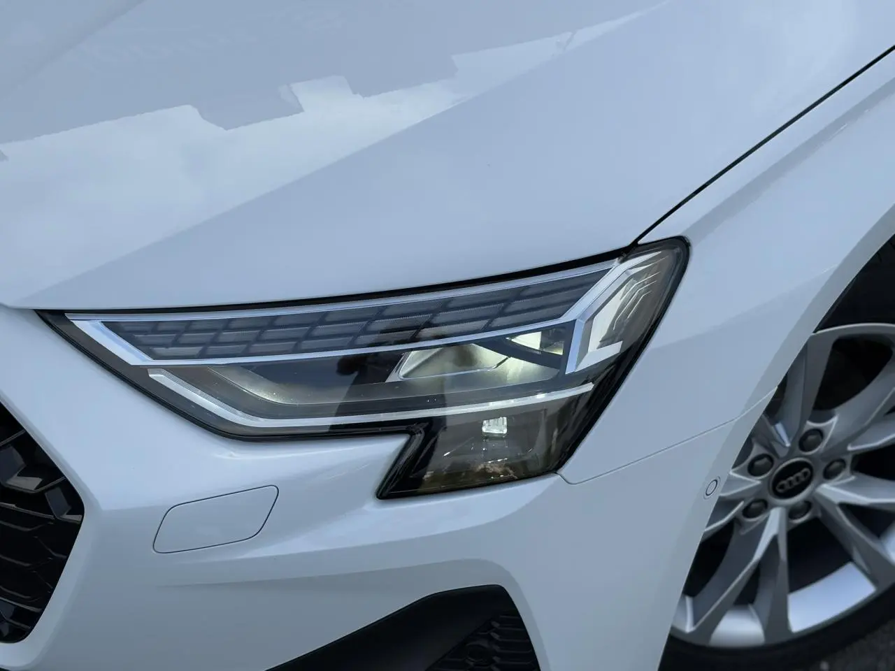 Gros plan sur le phare Matrix LED avant droit et la jante alliage 17 pouces de l'Audi A3 Sportback blanc Arkona.