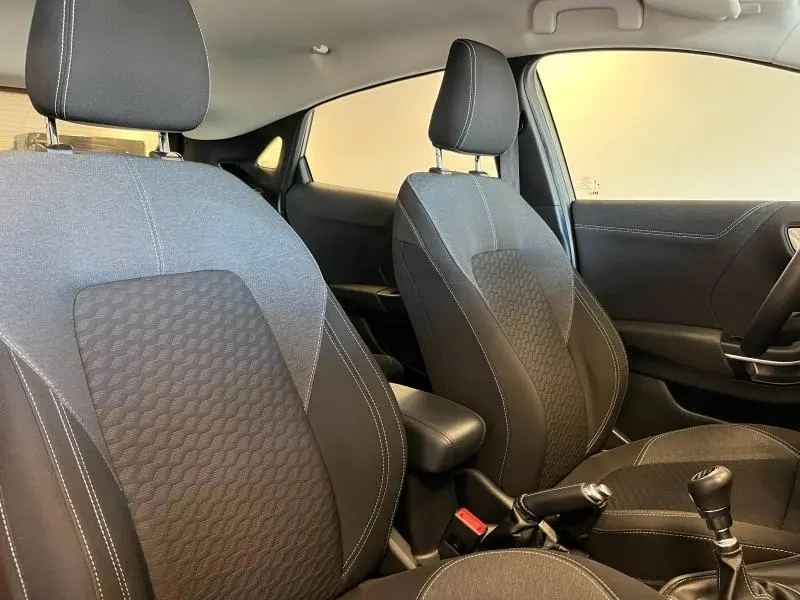 Vue intérieure côté conducteur et passager avant du Ford Puma 2022 avec sièges en tissu noir et coutures contrastées.