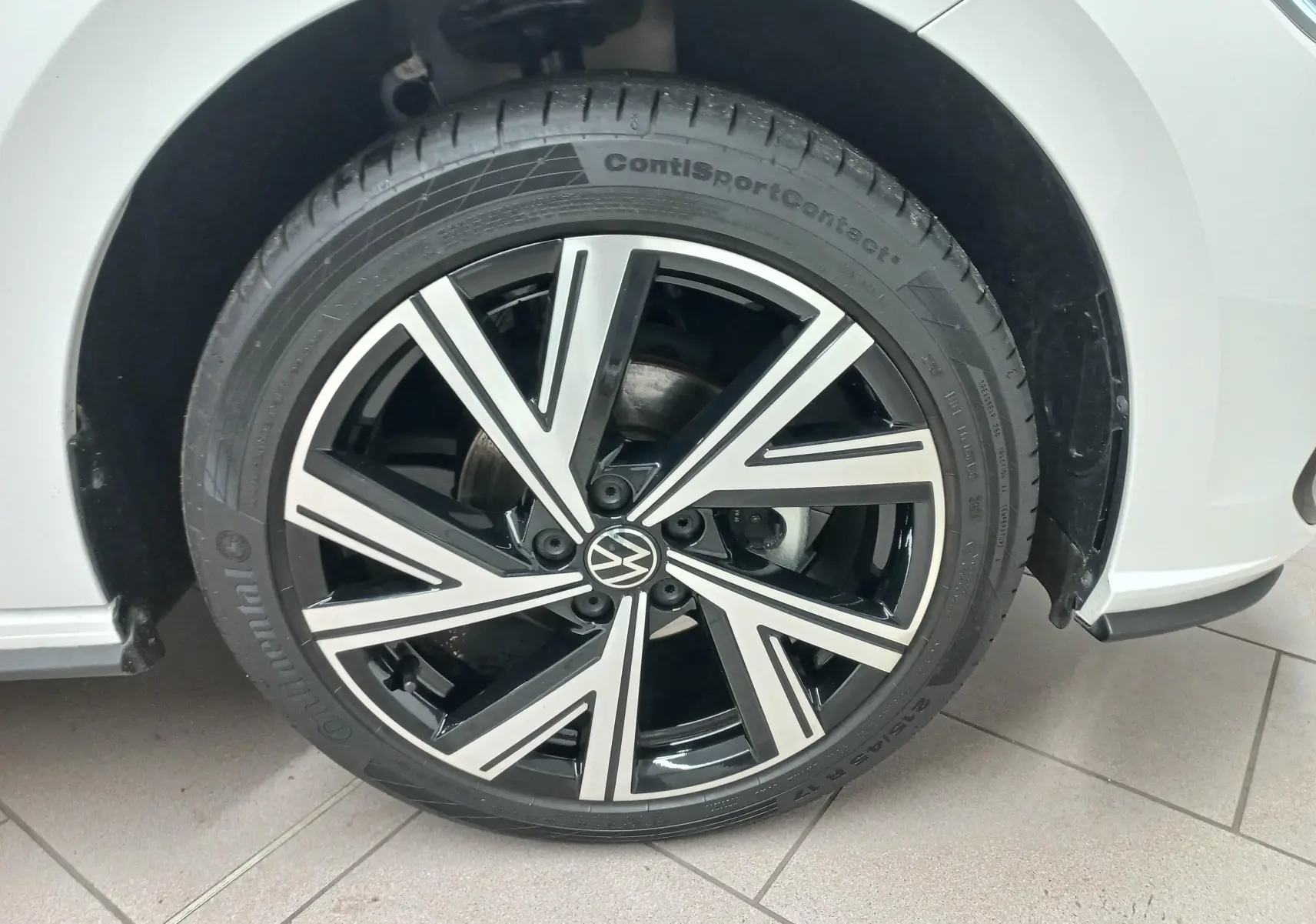 Gros plan sur la roue avant droite d'une Volkswagen Polo blanche avec jante alliage bicolore R-Line.