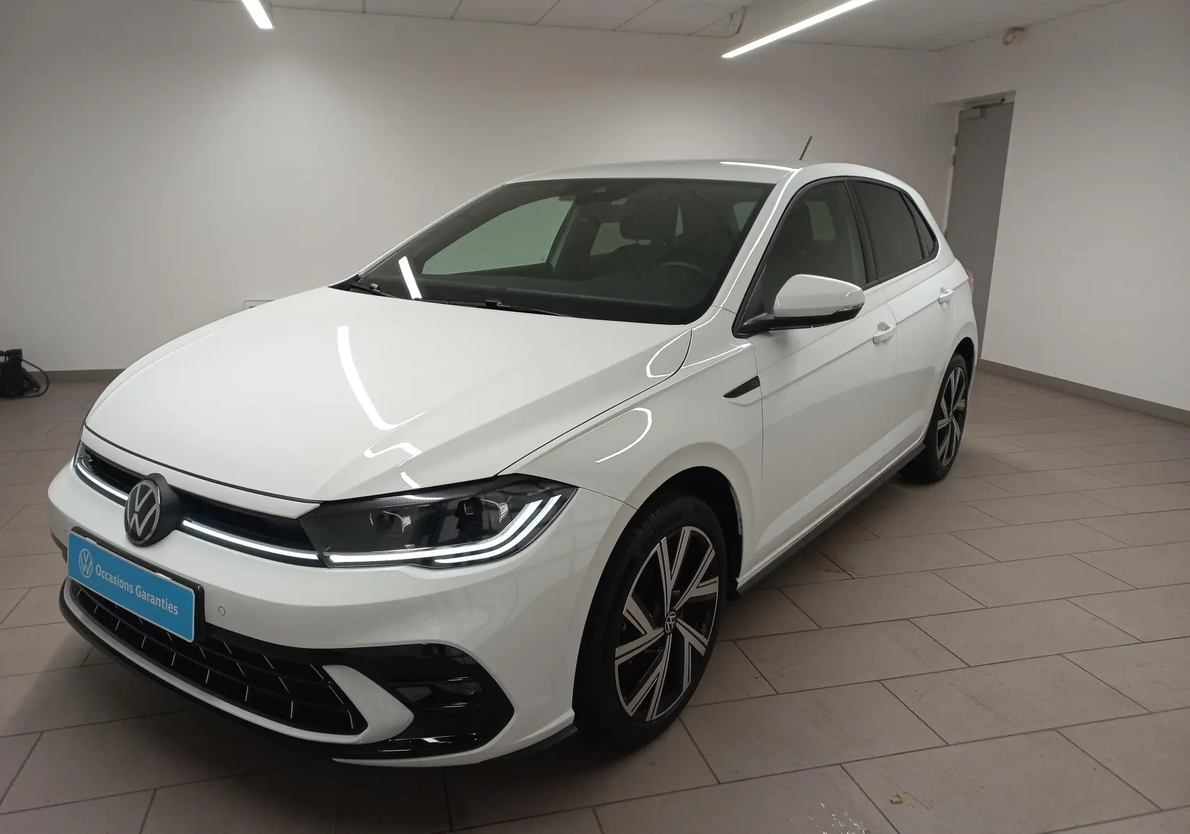 Volkswagen Polo blanc pur vue 3/4 avant droit avec phares LED et vitres arrière surteintées.