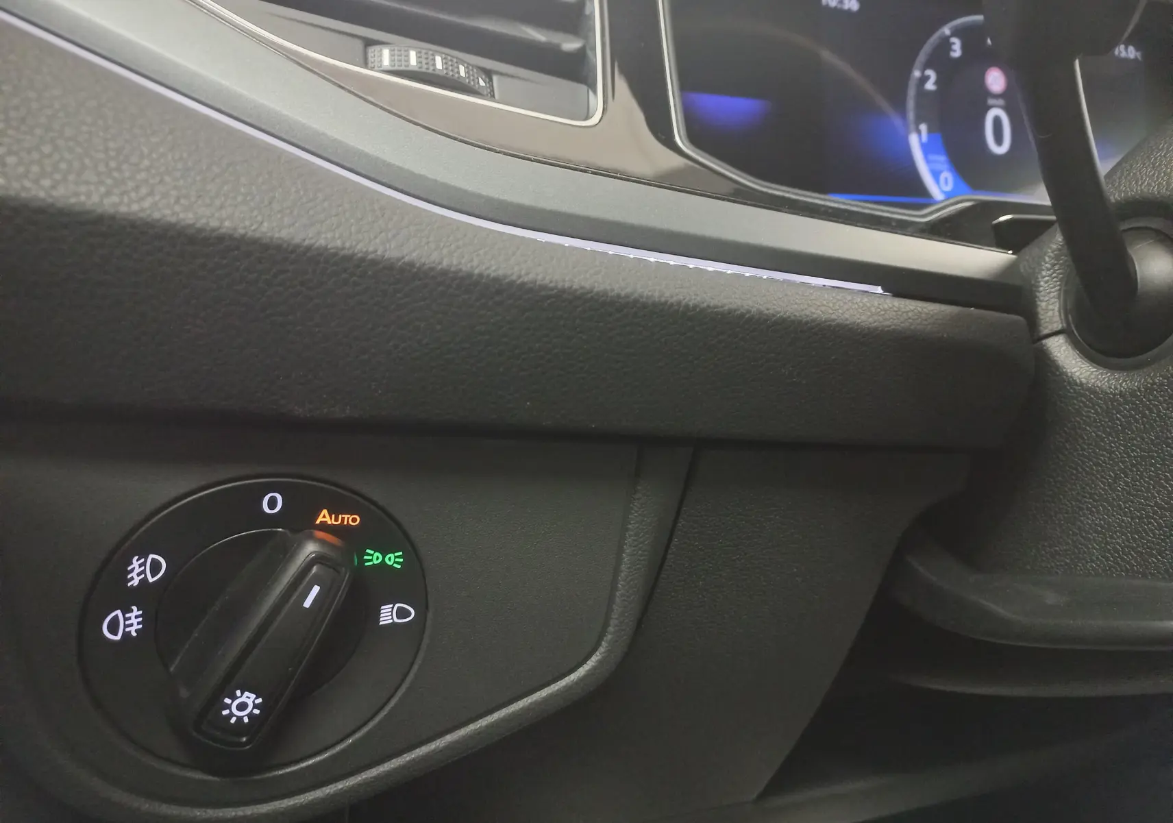 Gros plan sur le tableau de bord noir de la Volkswagen Polo 2025, avec commande d'éclairage et affichage numérique bleu.