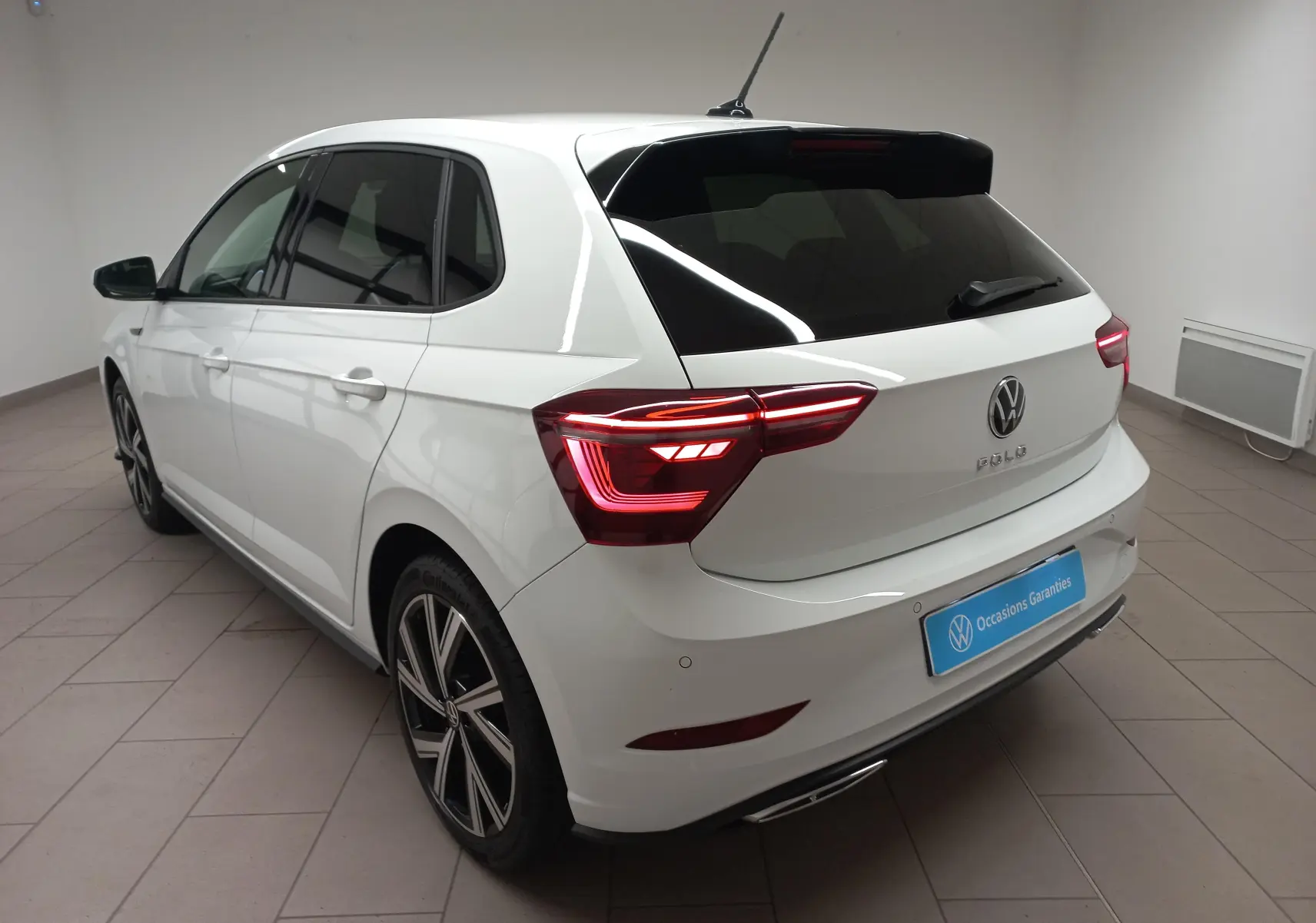 Volkswagen Polo blanc pur vue 3/4 arrière droit avec vitres arrière surteintées et feux LED allumés.