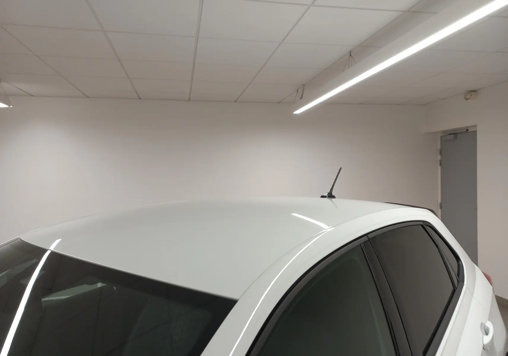 Vue partielle du toit et des vitres arrière surteintées d'une Volkswagen Polo Blanc Pur, version 2025 en intérieur.