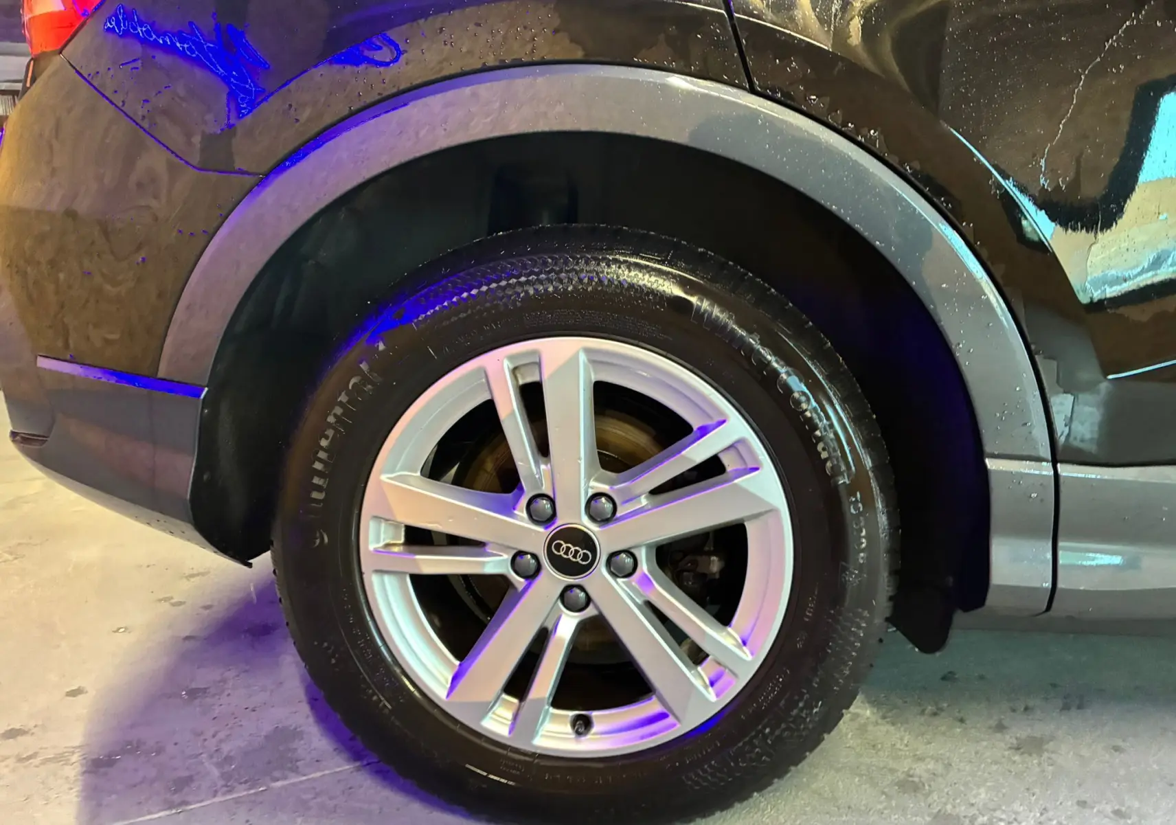 Gros plan sur la roue arrière droite avec jante alu argentée d’un Audi Q3 Sportback noir 2022.