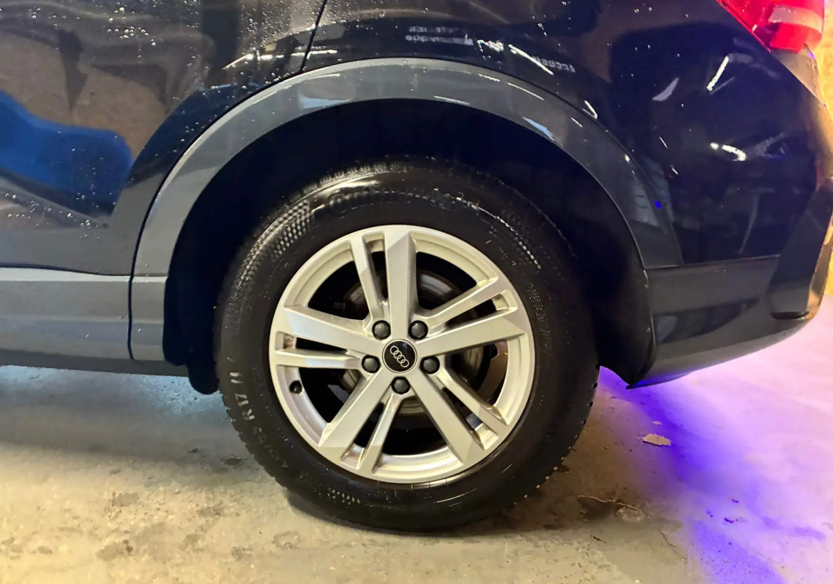 Gros plan sur la roue arrière droite d’un Audi Q3 Sportback noir avec jante alu cinq branches.