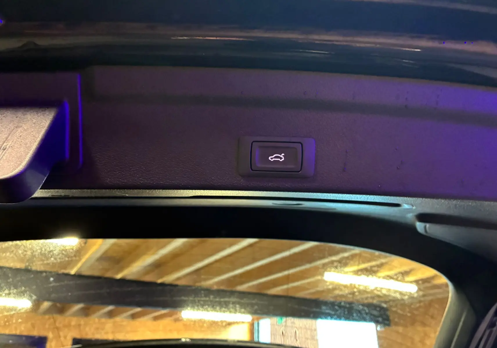 Bouton d'ouverture électrique du coffre visible sur le hayon intérieur d'un Audi Q3 Sportback noir.