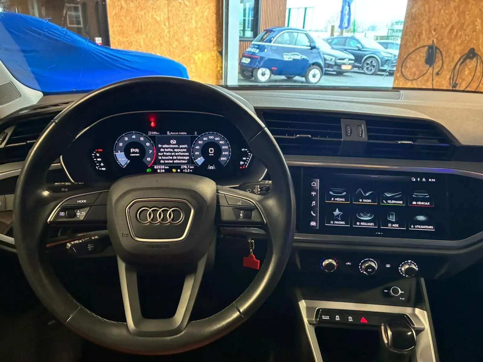 Vue intérieure centrée sur le volant cuir noir et l’écran tactile du tableau de bord de l’Audi Q3 Sportback 2022.