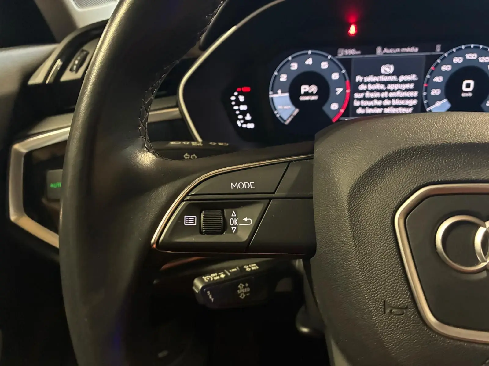 Gros plan sur le volant cuir multifonctions noir de l'Audi Q3 Sportback 2022 avec tableau de bord numérique éclairé.