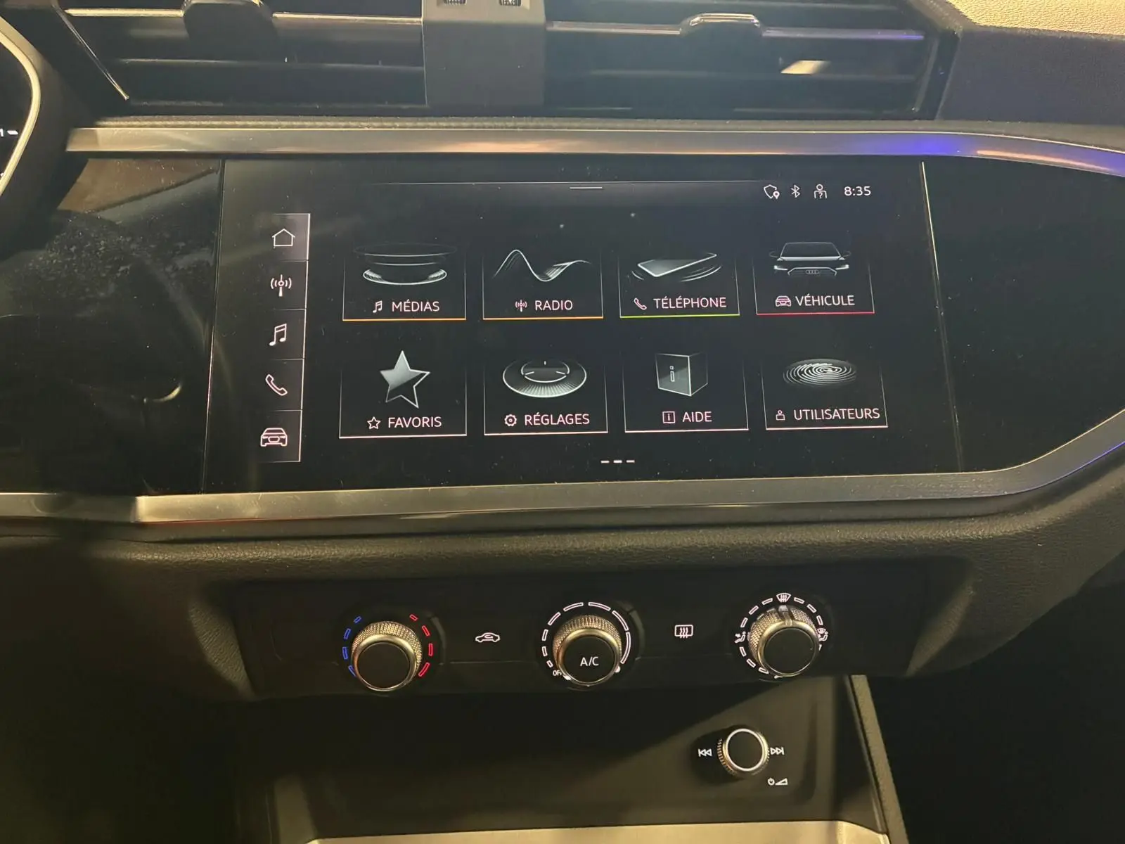 Vue rapprochée de l'écran tactile central et des commandes de climatisation de l'Audi Q3 Sportback noir 2022.