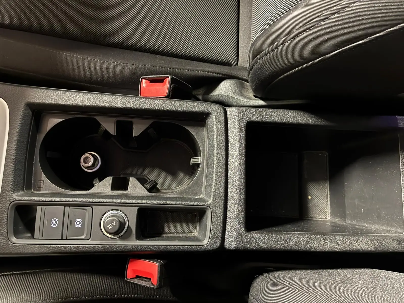 Gros plan sur la console centrale noire de l'Audi Q3 Sportback 2022 avec porte-gobelets et commandes électriques.