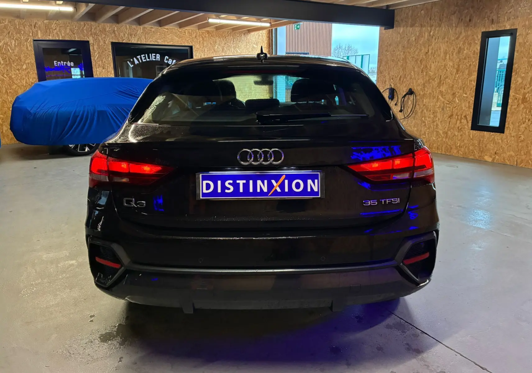 Vue arrière d'un Audi Q3 Sportback noir 2022 avec feux allumés dans un garage intérieur.