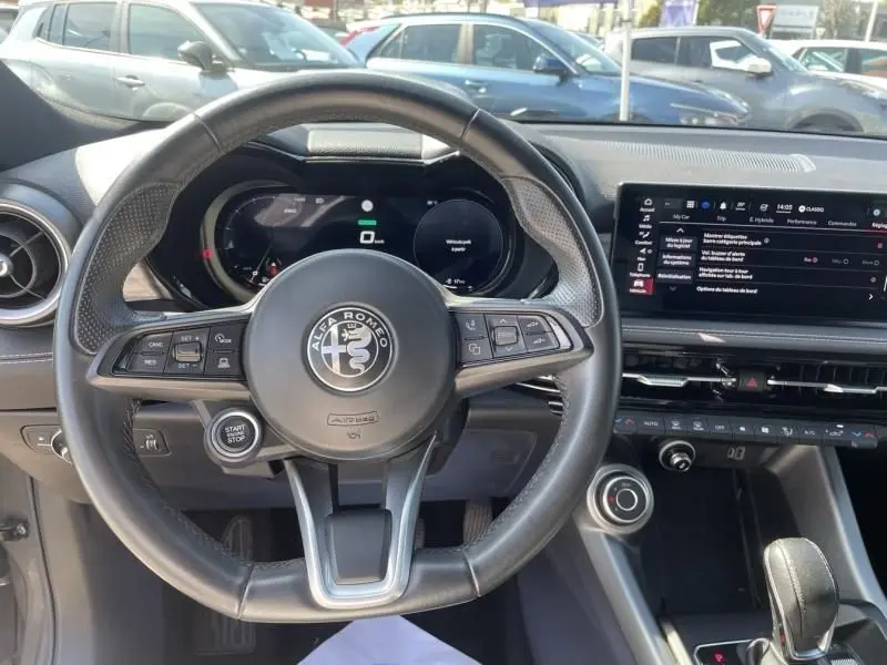 Vue intérieure centrée sur le volant noir de l'Alfa Romeo Tonale 2023, avec tableau de bord numérique et écran tactile visible.