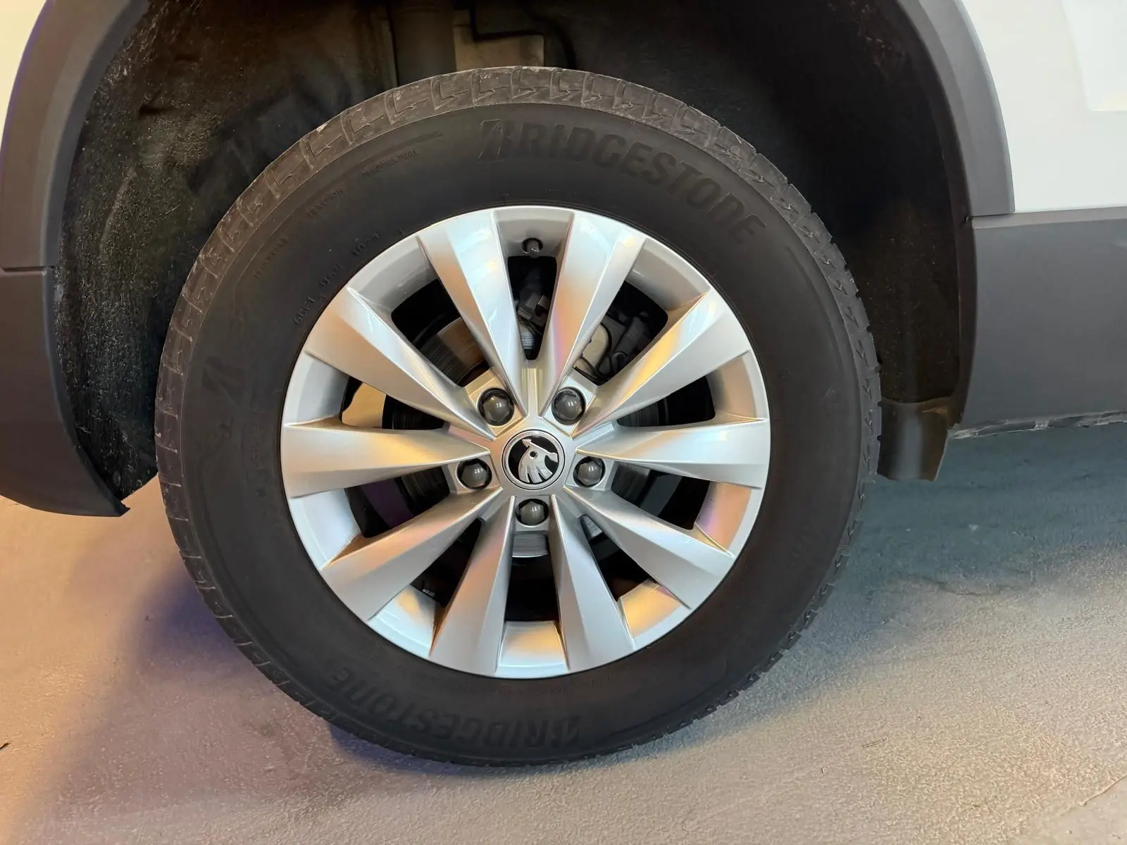 Gros plan sur la roue avant droite d’un Skoda Karoq blanc 2023 avec jante alliage et pneu Bridgestone.