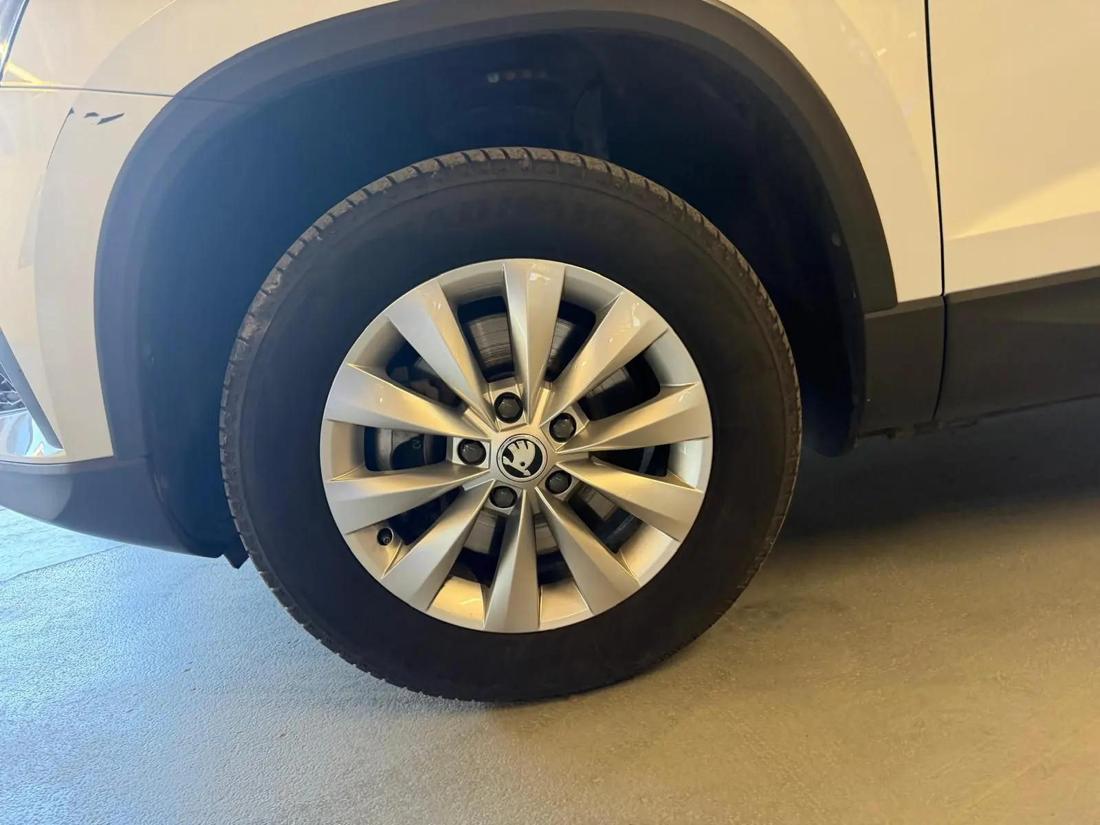 Gros plan sur la roue avant gauche du Skoda Karoq blanc 2023, mettant en valeur la jante alliage spécifique.