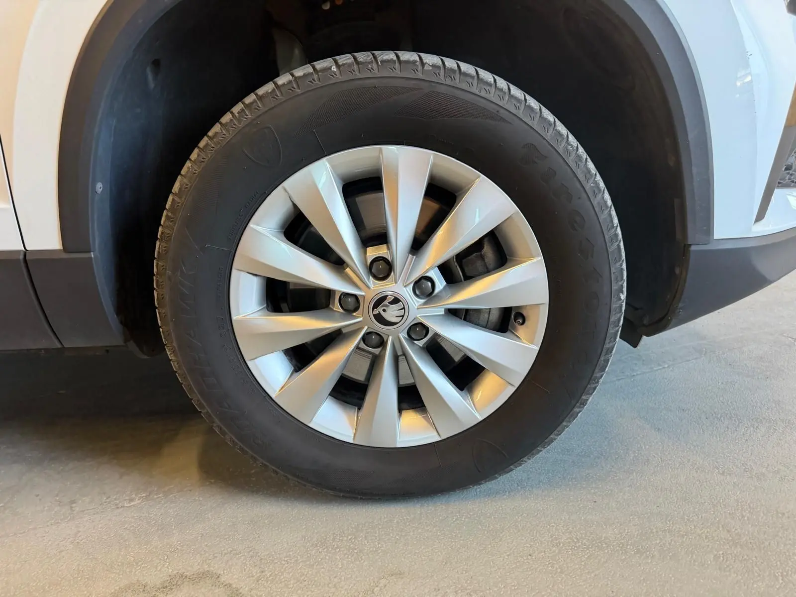 Gros plan sur la roue avant gauche du Skoda Karoq blanc 2023, mettant en valeur la jante alliage à dix branches.