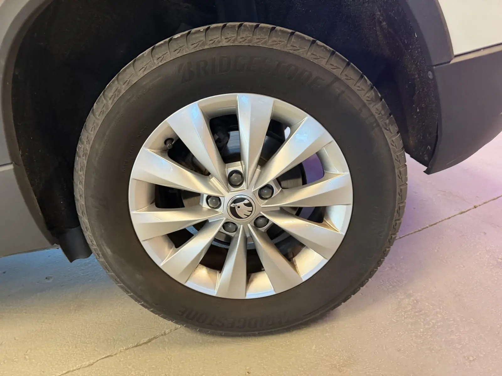 Gros plan sur la roue avant gauche du Skoda Karoq blanc 2023, avec jante alliage argentée et pneu Bridgestone.