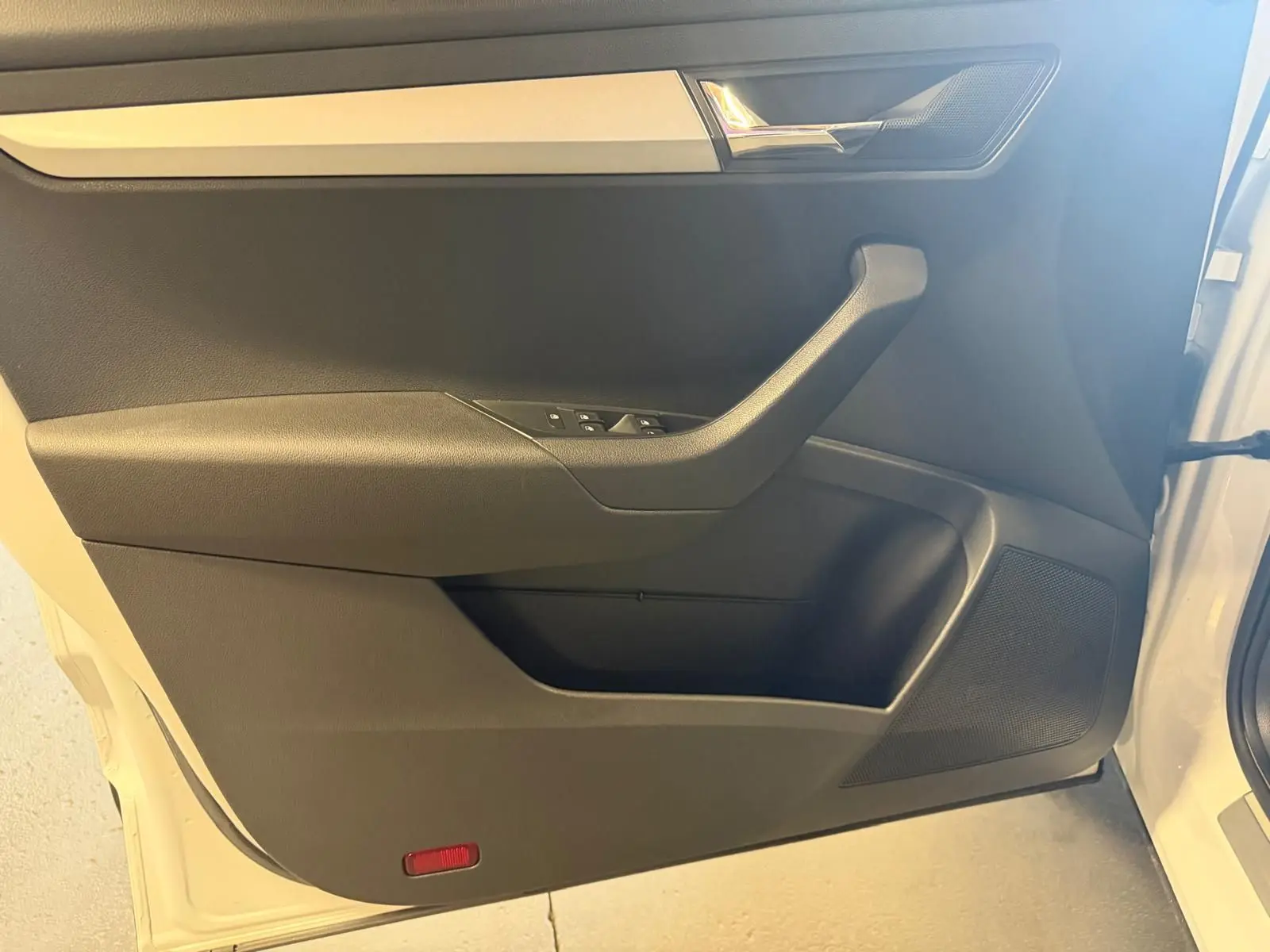Intérieur côté gauche de la porte avant d'un Skoda Karoq blanc 2023, avec poignée et commandes de vitres visibles.