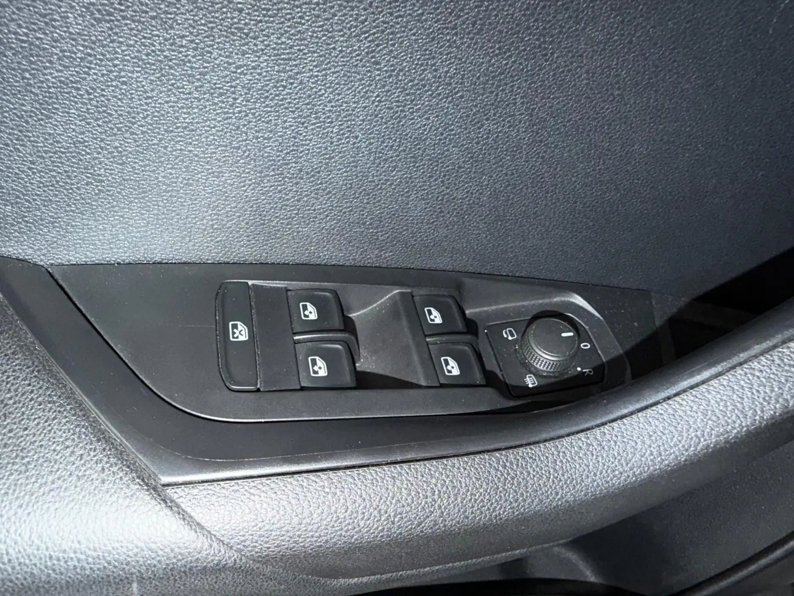 Gros plan sur les commandes des vitres et rétroviseurs côté conducteur du Skoda Karoq blanc 2023.