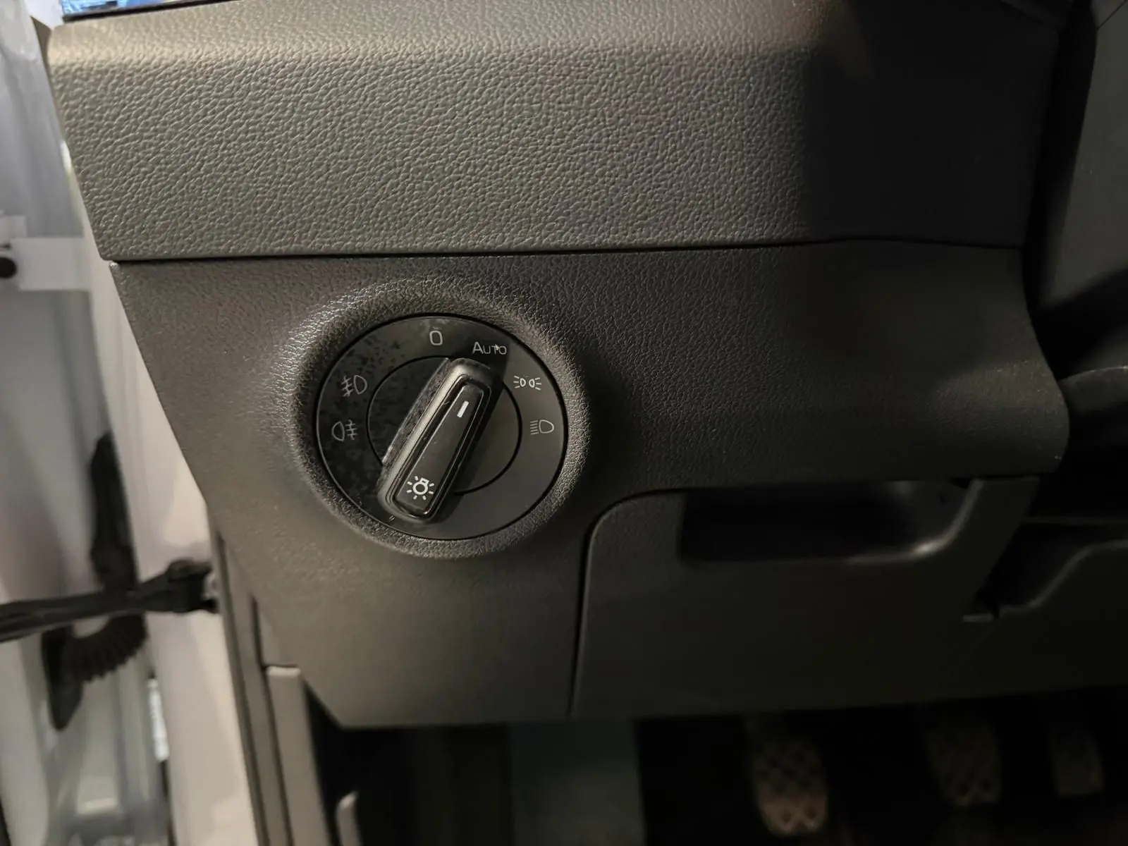 Détail du bouton de commande des phares sur la partie gauche du tableau de bord d’un Skoda Karoq blanc 2023.