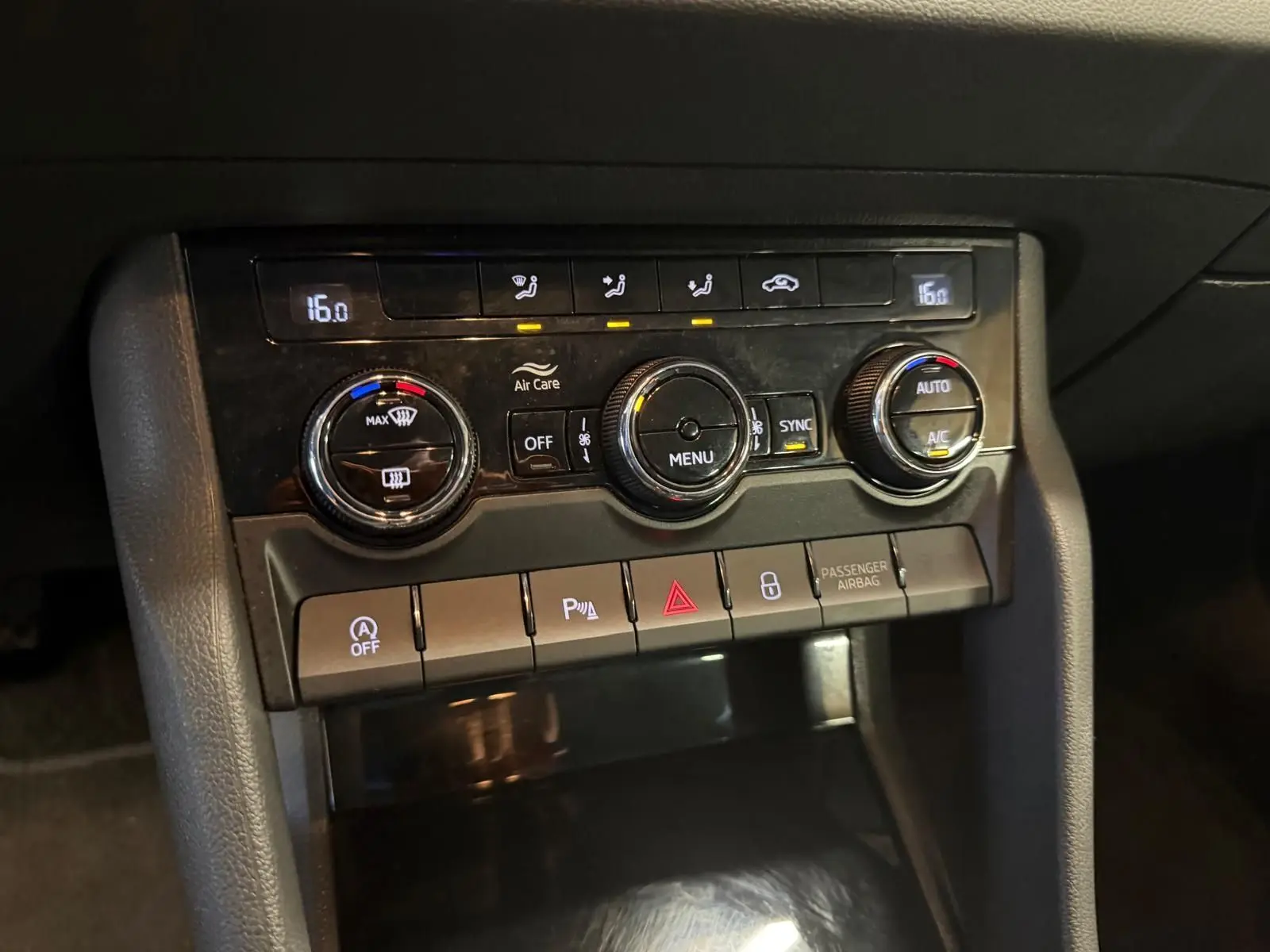 Gros plan sur la console centrale du Skoda Karoq blanc 2023, avec commandes de climatisation et boutons fonctionnels.