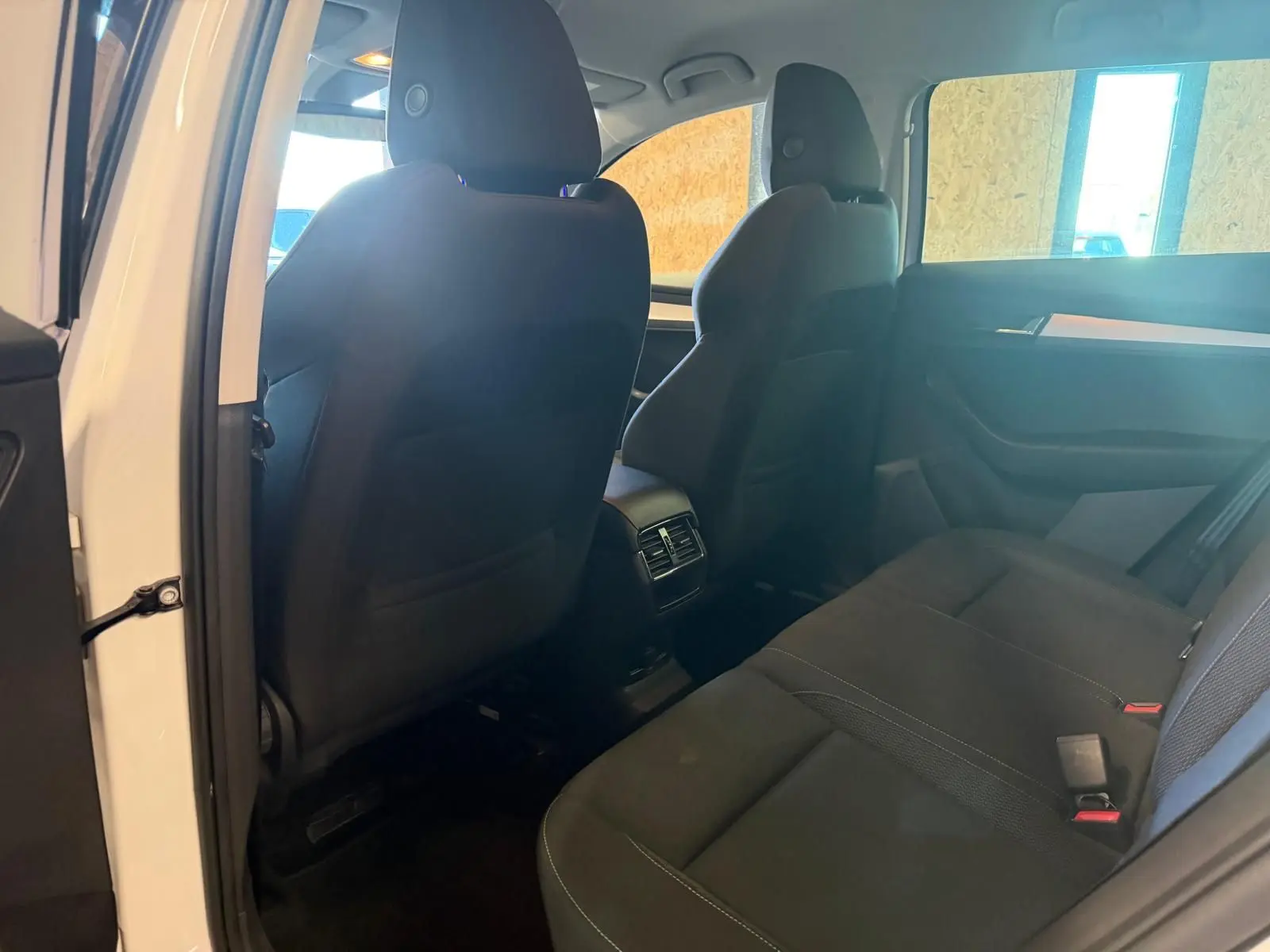 Vue intérieure arrière du Skoda Karoq blanc 2023, montrant les sièges noirs et les aérateurs centraux arrière.