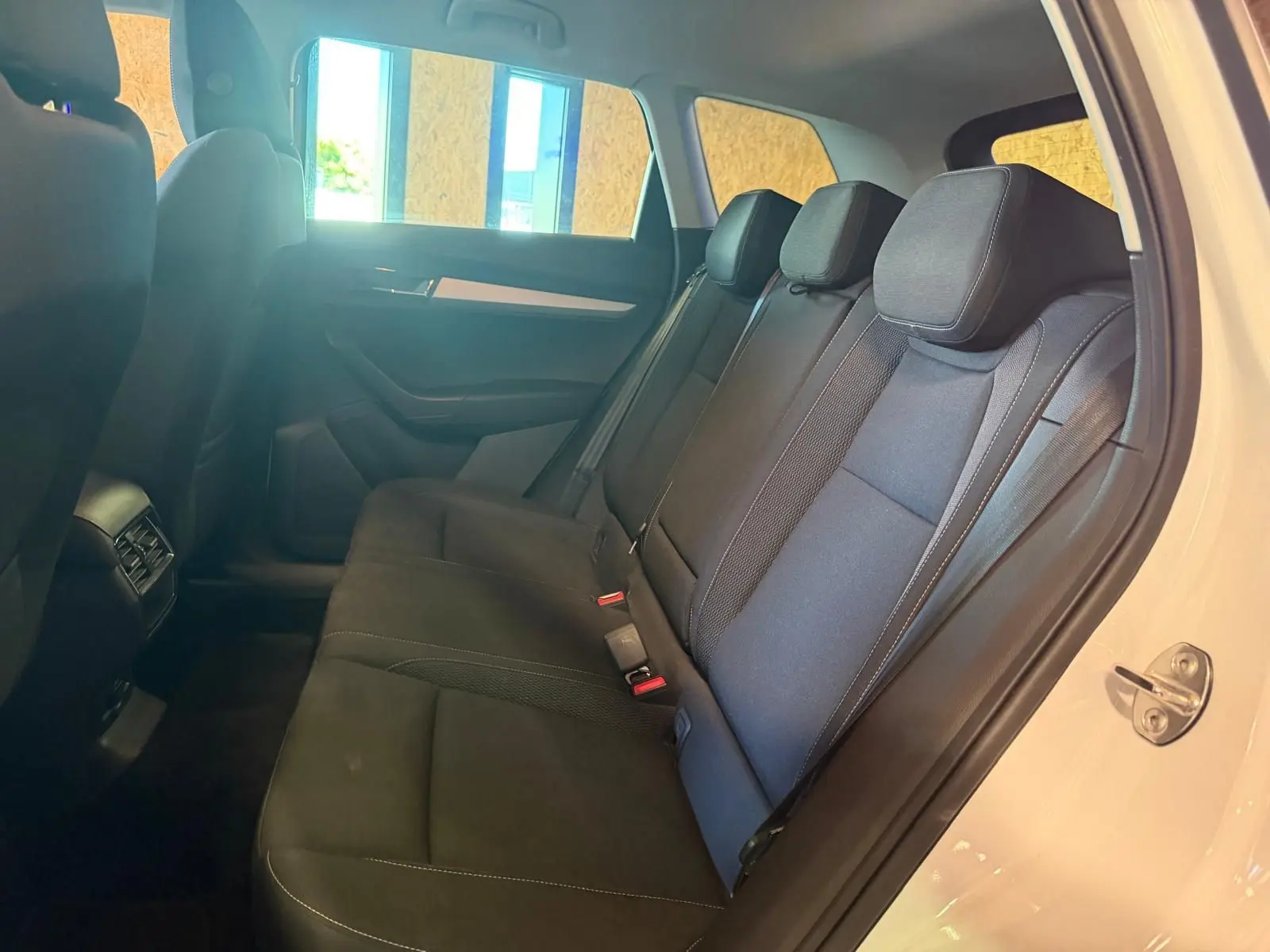 Vue intérieure côté droit sur les sièges arrière noirs du Skoda Karoq blanc 2023, porte arrière ouverte.