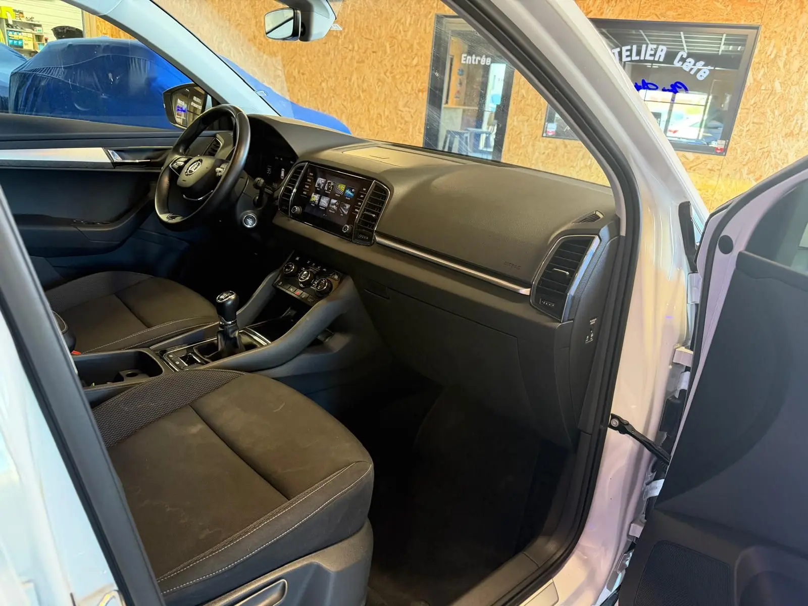 Intérieur avant droit du Skoda Karoq blanc 2023, montrant tableau de bord, volant et levier de vitesses manuel.