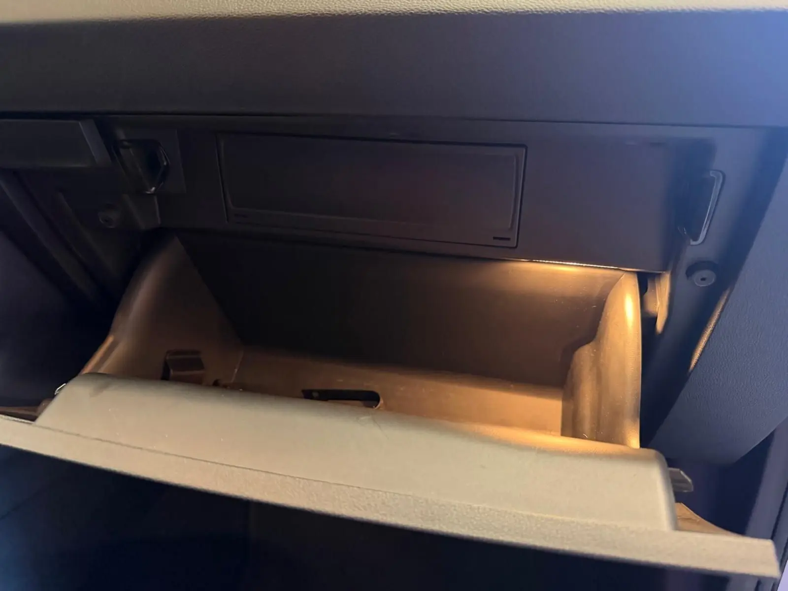 Vide-boîte à gants éclairé dans l’habitacle sombre d’un Skoda Karoq 1.5 TSI blanc, version Ambition 2023.