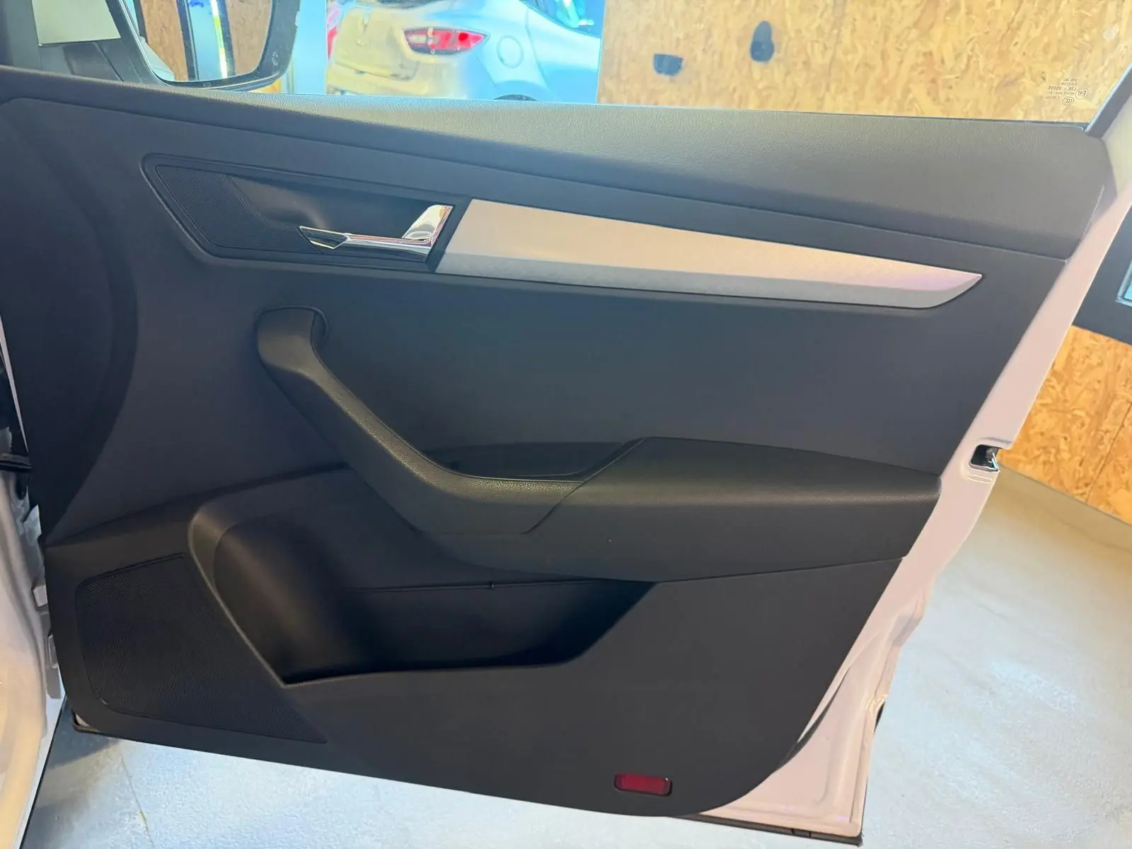 Vue intérieure de la porte avant gauche d’un Skoda Karoq blanc 2023, avec garniture noire et insert argenté.