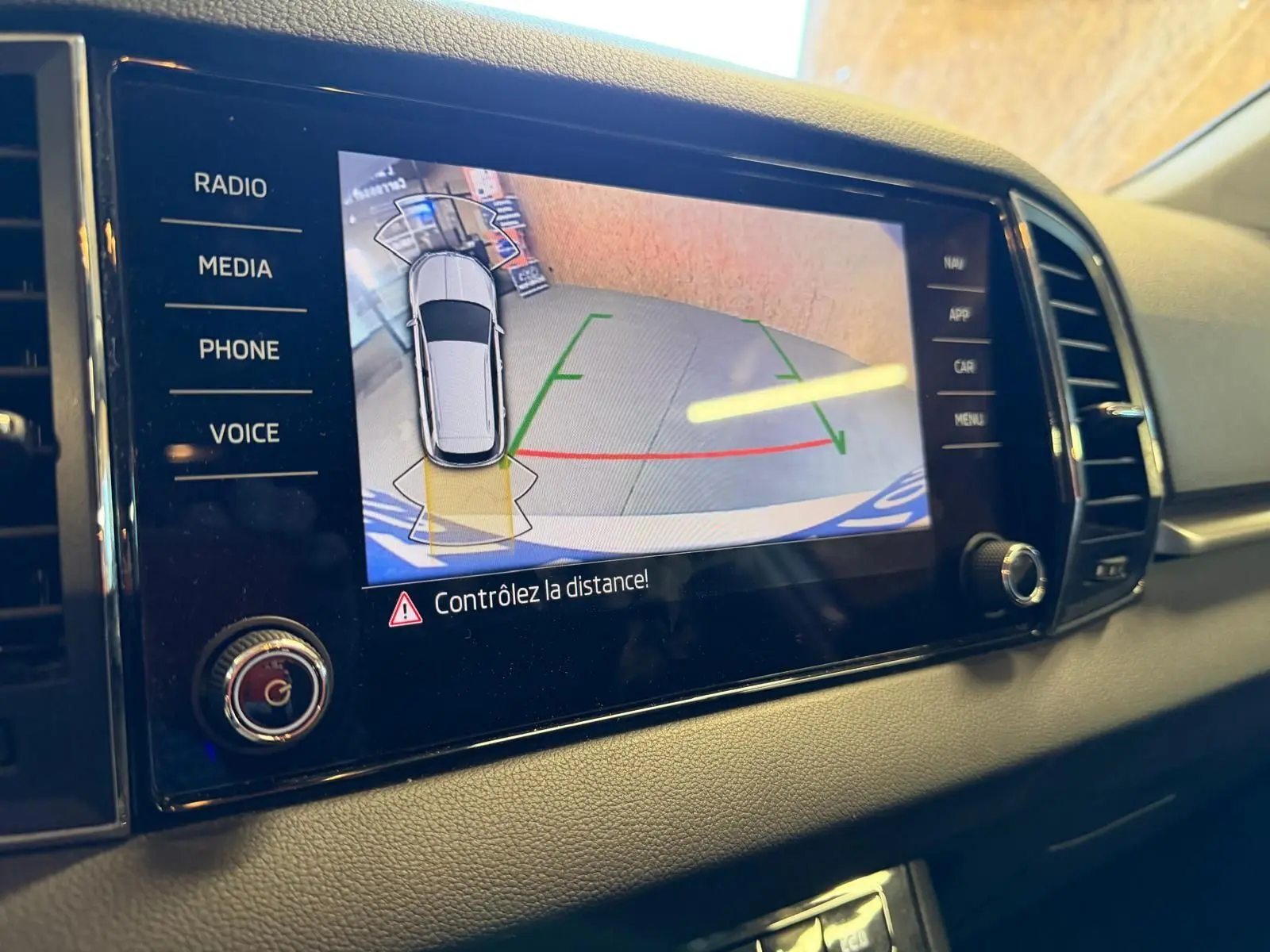 Écran central du Skoda Karoq blanc 2023 montrant la caméra de recul avec alertes de distance, vue intérieure côté droit.
