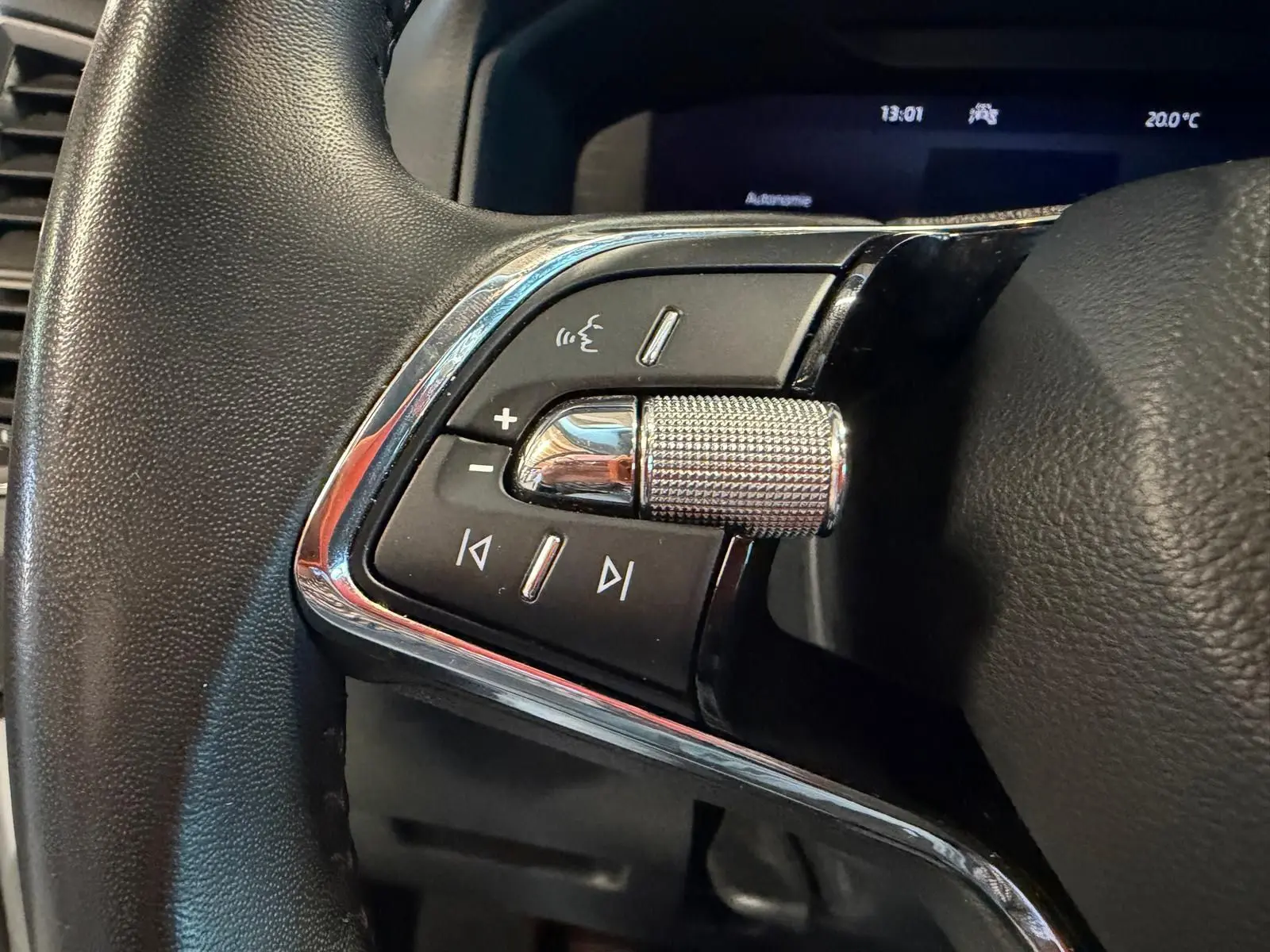 Gros plan sur les commandes gauche du volant du Skoda Karoq blanc 2023, avec molette et boutons multifonctions.