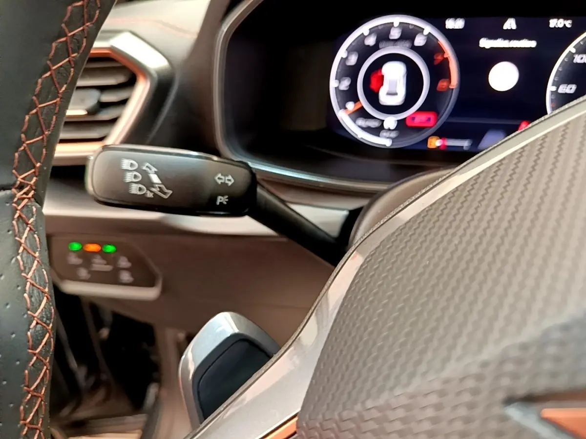 Gros plan sur le volant en cuir avec surpiqûres orange et tableau de bord numérique du CUPRA Formentor gris foncé.