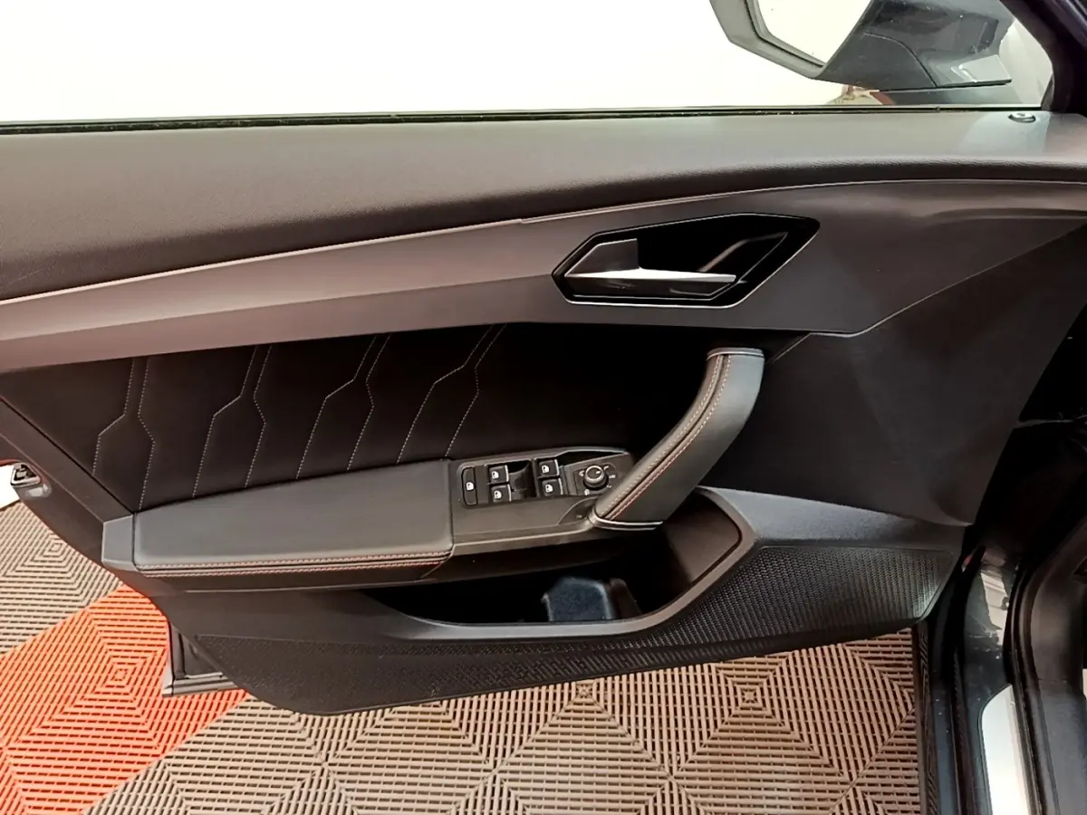 Vue côté gauche sur la porte intérieure noire du CUPRA Formentor 2022 avec surpiqûres rouges et commandes électriques.
