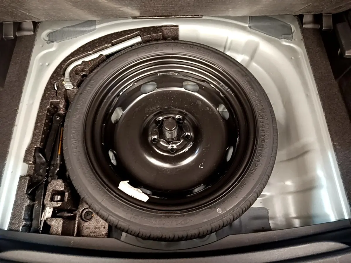 Vue plongeante sur la roue de secours galette noire dans le coffre gris clair du CUPRA Formentor 2022.